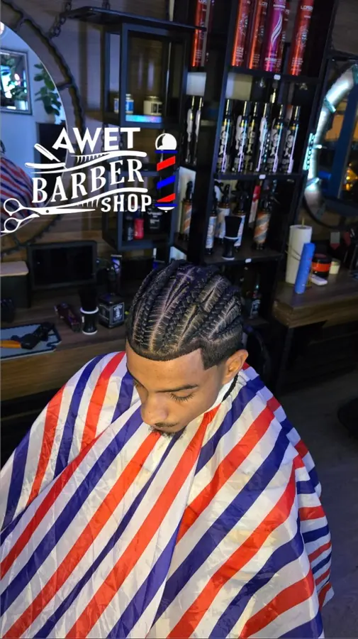Frisch geflochtene Cornrows, der Kunde trägt einen rot-weiss-blau gestreiften Umhang